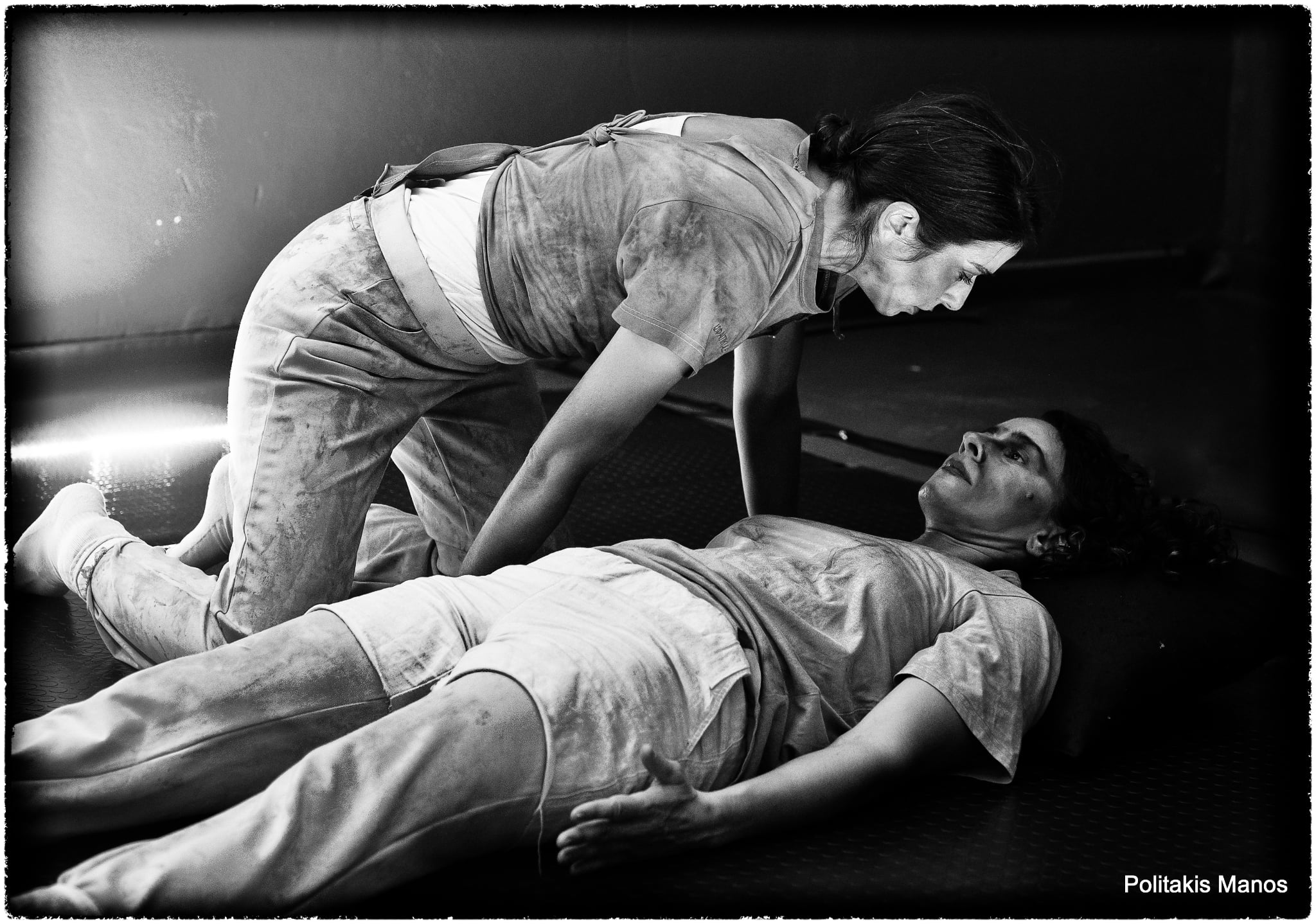 Two performers face each other at close range on the floor in Sonderkommando.